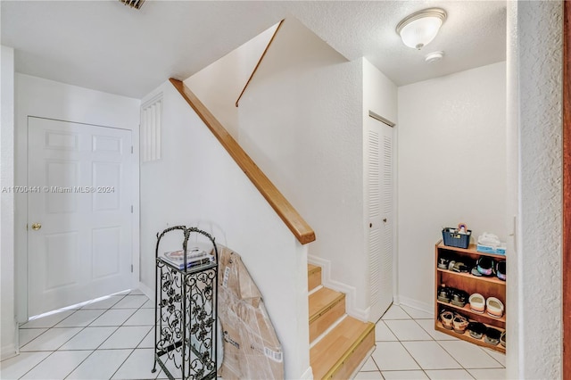 stairs with tile patterned floors and a textured ceiling