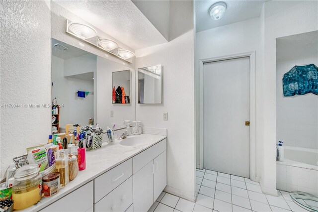 bathroom with tiled tub, tile patterned flooring, and vanity