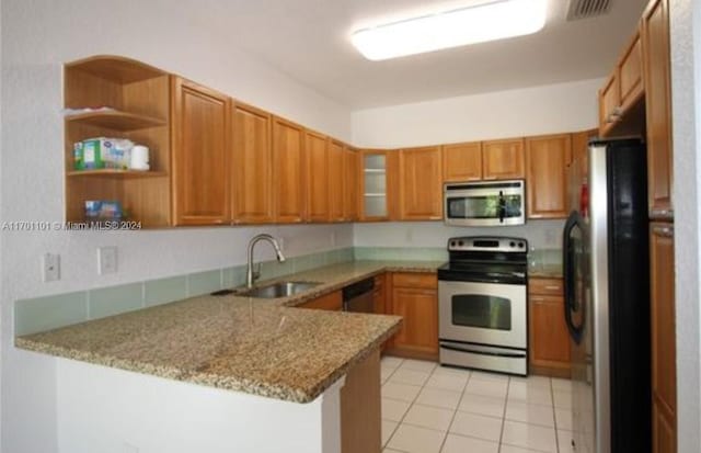 kitchen with sink, light stone countertops, light tile patterned floors, kitchen peninsula, and stainless steel appliances