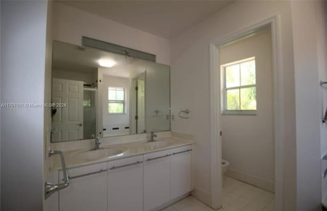 bathroom with tile patterned flooring, vanity, toilet, and a wealth of natural light