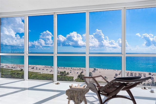 unfurnished sunroom featuring plenty of natural light, a view of the beach, and a water view