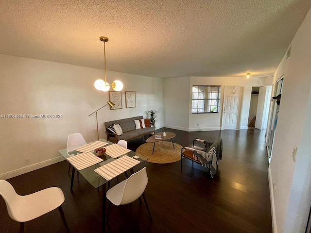 dining space featuring dark wood-type flooring, an inviting chandelier, and a textured ceiling