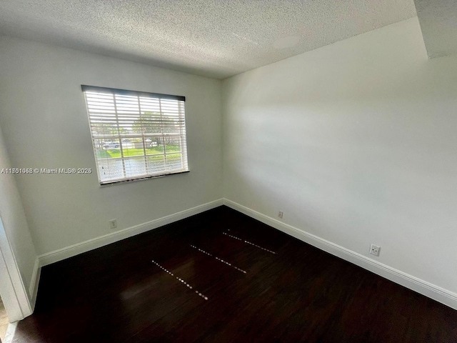 empty room with dark wood-type flooring and a textured ceiling