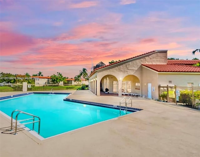 pool at dusk featuring a patio