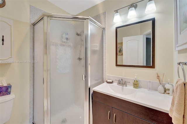 bathroom featuring vanity, toilet, and a shower with door