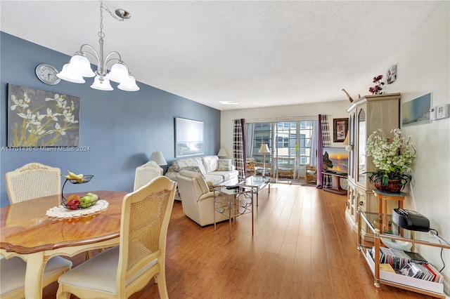 dining room featuring light hardwood / wood-style floors, a textured ceiling, and an inviting chandelier