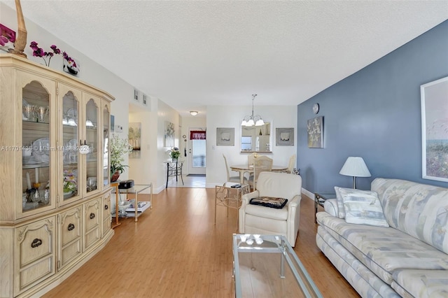 living room featuring an inviting chandelier, a textured ceiling, and light hardwood / wood-style flooring