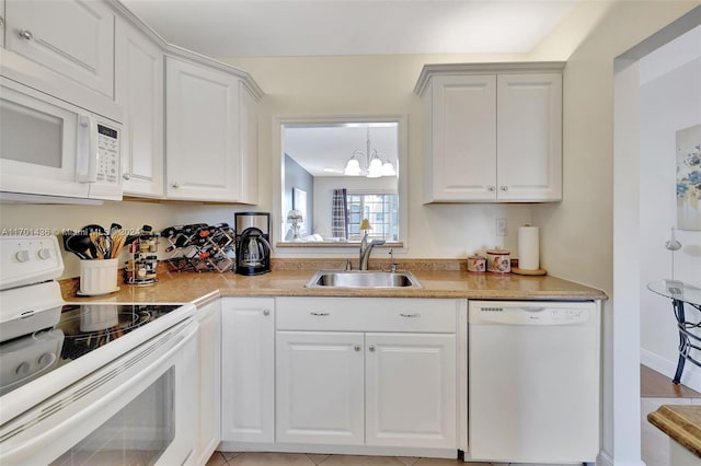 kitchen with white appliances, white cabinetry, an inviting chandelier, and sink