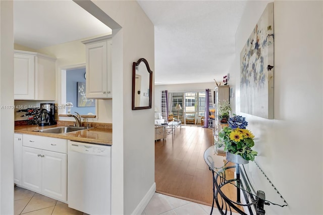 kitchen featuring white cabinets, dishwasher, sink, and light hardwood / wood-style flooring