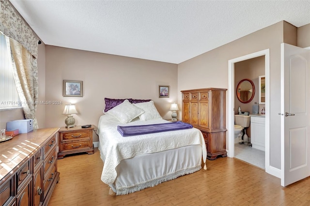 bedroom featuring a textured ceiling, connected bathroom, and light hardwood / wood-style flooring