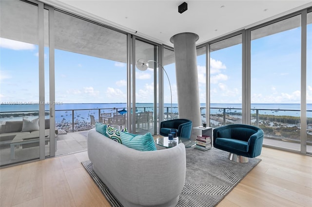 living room with a water view, a wall of windows, and light hardwood / wood-style floors