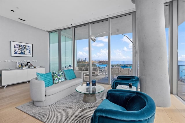 living room with light hardwood / wood-style floors, expansive windows, and a water view