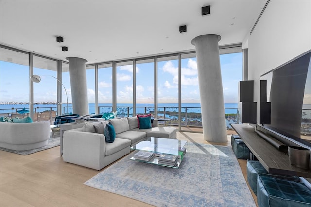 living room featuring expansive windows, a water view, and light hardwood / wood-style flooring