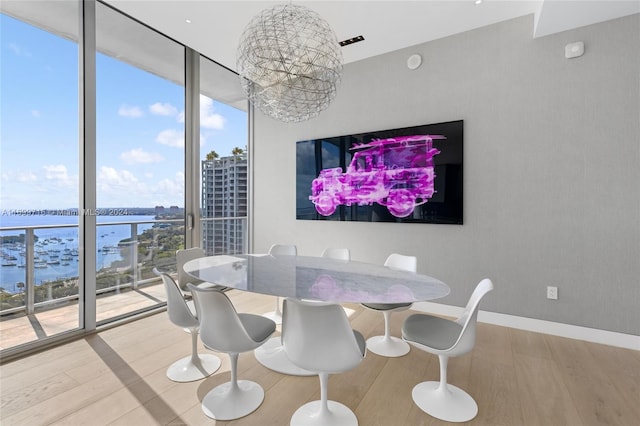 dining space with a wealth of natural light, hardwood / wood-style floors, a water view, and a wall of windows