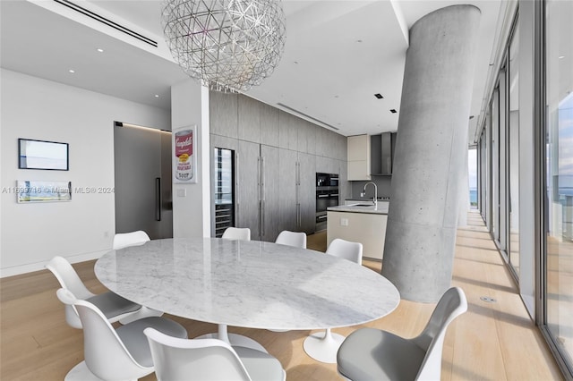 dining area with sink, a chandelier, and light hardwood / wood-style floors