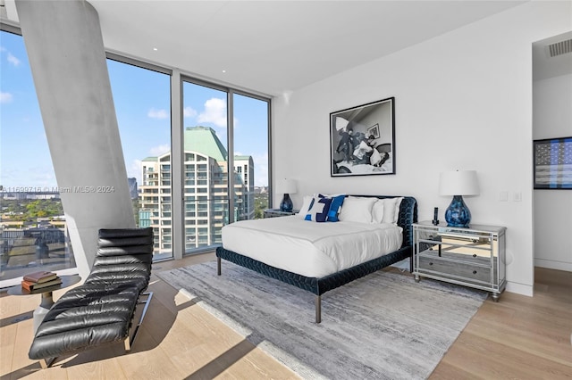 bedroom with a wall of windows, light hardwood / wood-style floors, and multiple windows