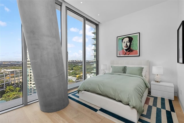 bedroom featuring access to exterior, light hardwood / wood-style flooring, and a wall of windows