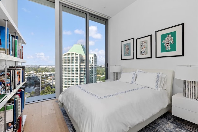 bedroom with expansive windows and wood-type flooring