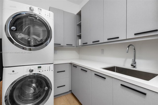 2675 S Bayshore Dr Unit 1602S, Miami, FL 33133 - washroom with stacked washing machine and dryer, cabinet space, and light wood finished floors