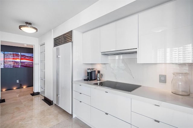 kitchen featuring built in refrigerator, black electric cooktop, white cabinetry, and decorative backsplash