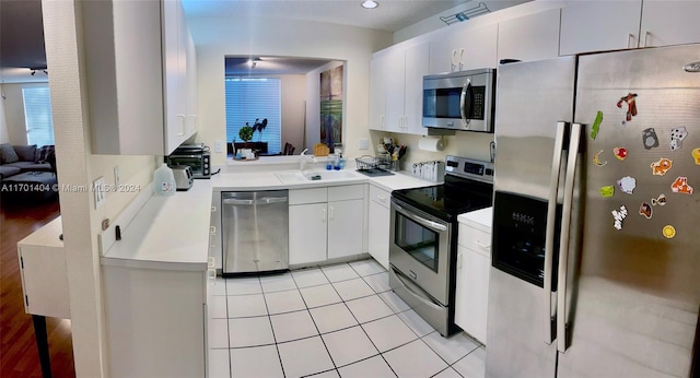 kitchen with light tile patterned flooring, sink, white cabinets, and stainless steel appliances