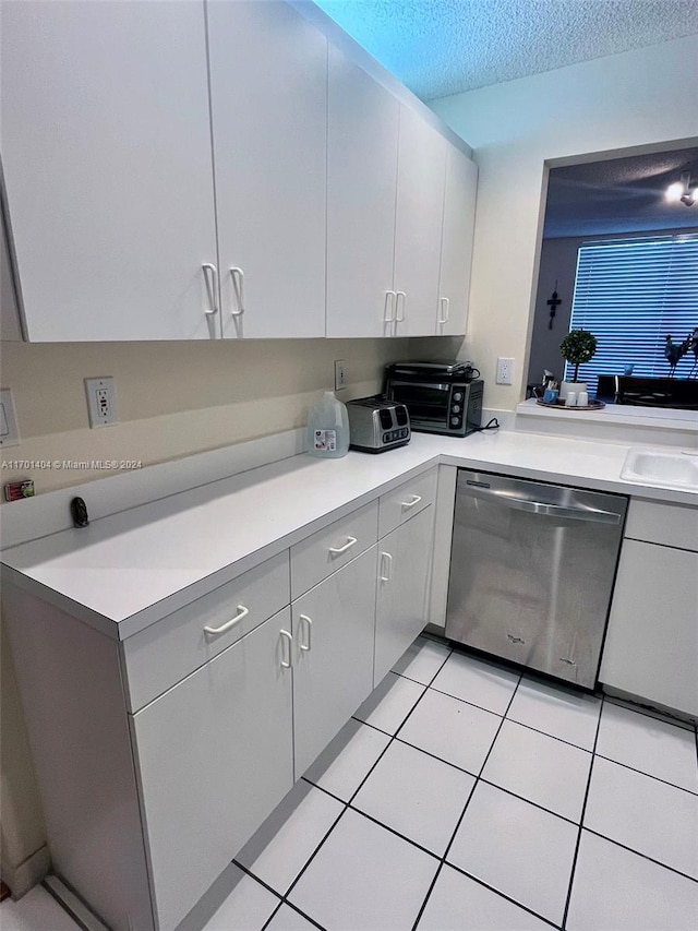 kitchen featuring dishwasher, sink, a textured ceiling, gray cabinets, and light tile patterned floors