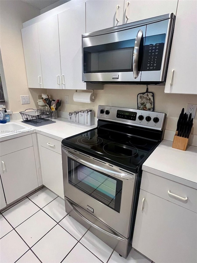 kitchen with white cabinets, light tile patterned floors, stainless steel appliances, and sink