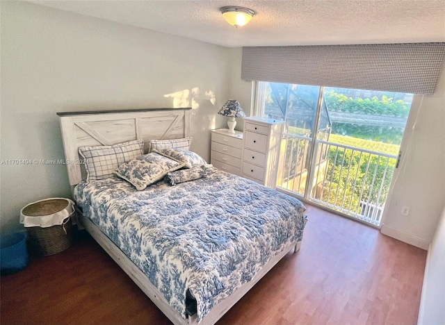 bedroom featuring access to exterior, a textured ceiling, and hardwood / wood-style flooring