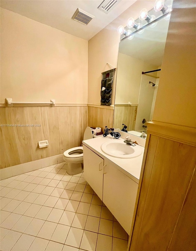 bathroom with tile patterned flooring, vanity, toilet, and wooden walls