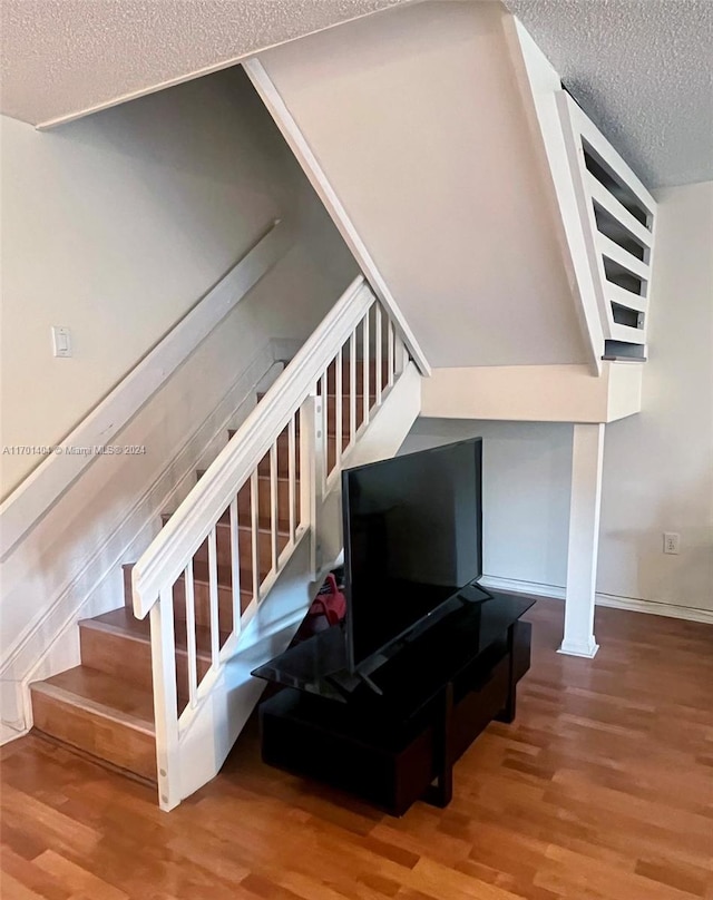 stairway with hardwood / wood-style floors and a textured ceiling