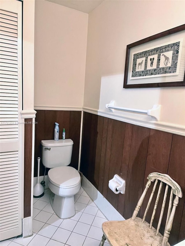 bathroom with wood walls, tile patterned flooring, and toilet