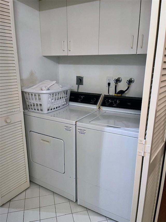 laundry room featuring cabinets, light tile patterned floors, and washer and clothes dryer