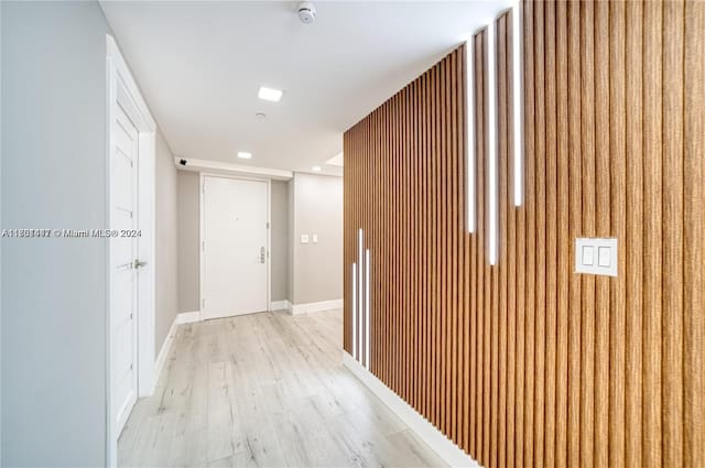 hall featuring light wood-type flooring and wooden walls