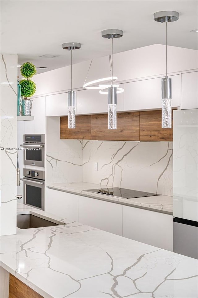 kitchen featuring pendant lighting, stainless steel double oven, white cabinetry, and electric stovetop