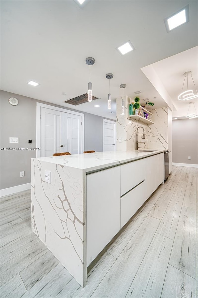 kitchen featuring kitchen peninsula, light hardwood / wood-style flooring, white cabinets, and pendant lighting