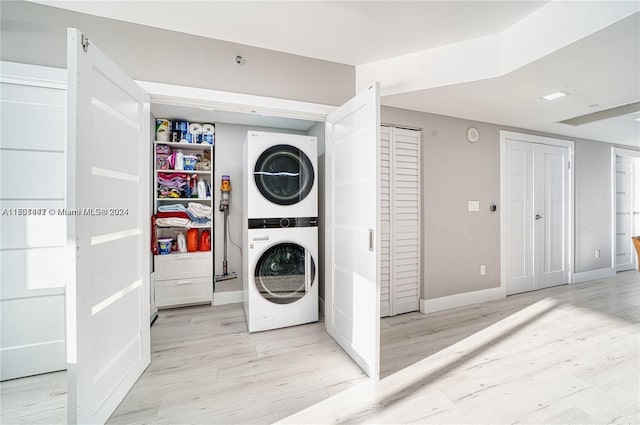 laundry area with stacked washer / dryer and light wood-type flooring