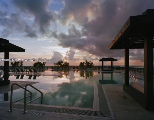 pool at dusk featuring a water view