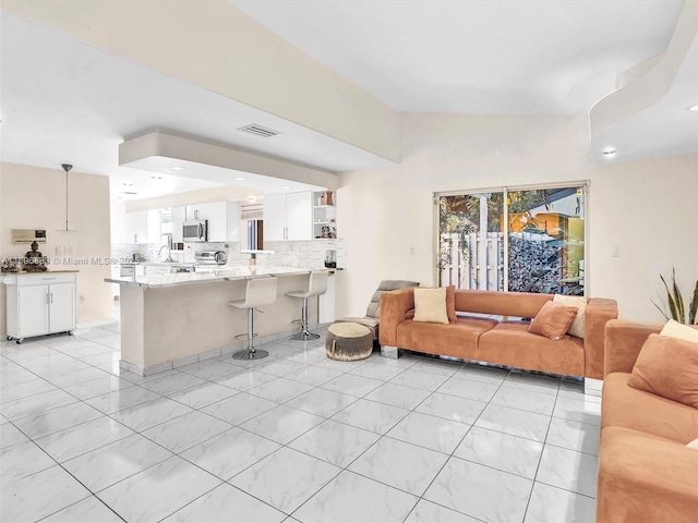 living room with lofted ceiling, a wealth of natural light, light tile patterned flooring, and visible vents