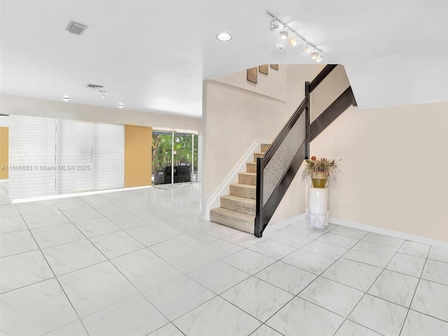 interior space with rail lighting, visible vents, baseboards, and stairs