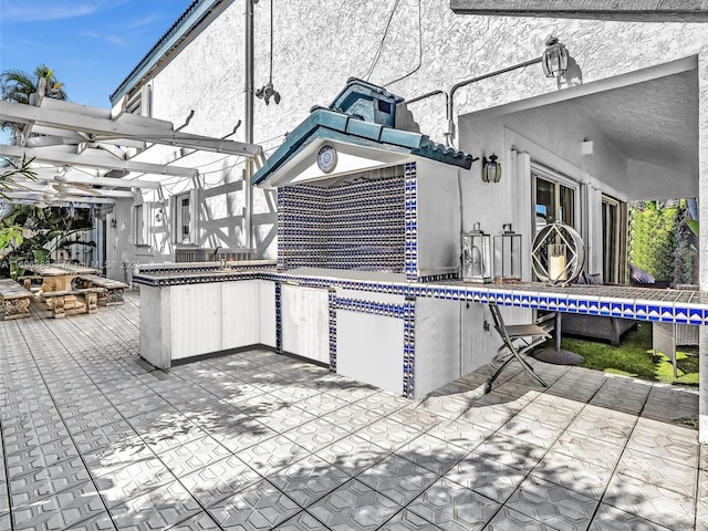 exterior space featuring a pergola, a patio, and stucco siding