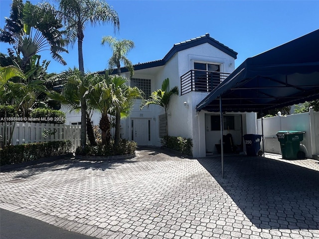 view of front of home with a tiled roof, fence, a balcony, and stucco siding