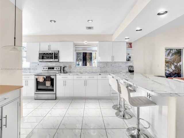 250 NE 212th St, Miami, FL 33179 - kitchen with appliances with stainless steel finishes, a peninsula, open shelves, white cabinetry, and recessed lighting