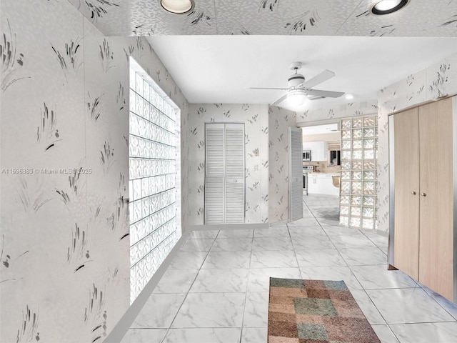 corridor featuring marble finish floor and wallpapered walls