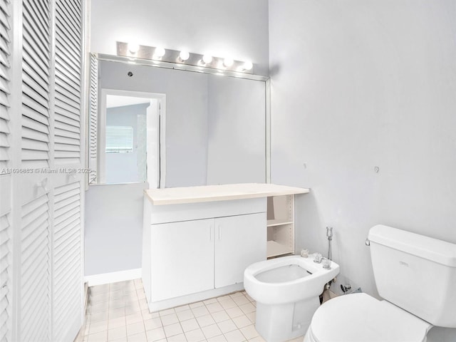 bathroom featuring toilet, tile patterned floors, vanity, a bidet, and a closet