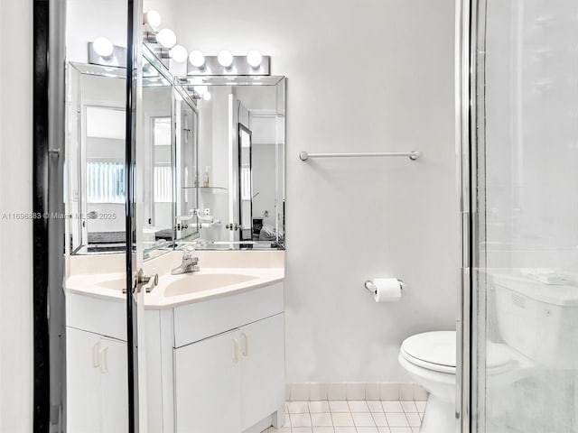 full bathroom featuring baseboards, toilet, a shower with door, tile patterned floors, and vanity