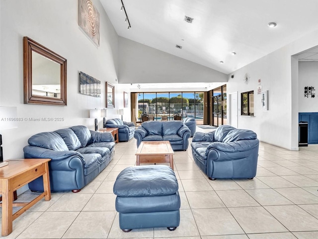 living area featuring high vaulted ceiling, rail lighting, light tile patterned flooring, and visible vents