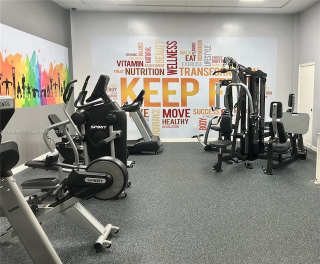 workout area with a paneled ceiling and baseboards