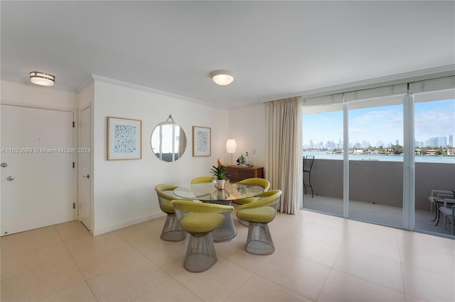 tiled dining area with a water view and crown molding