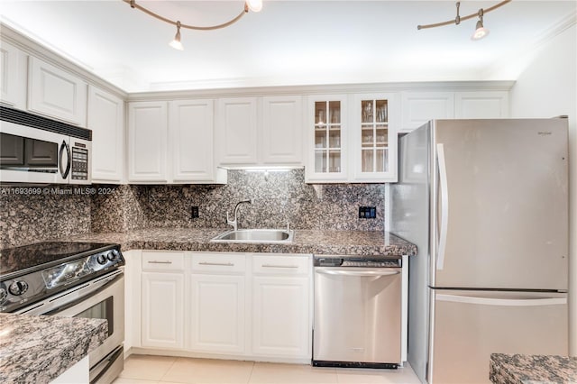 kitchen featuring white cabinetry, sink, stainless steel appliances, dark stone countertops, and light tile patterned floors