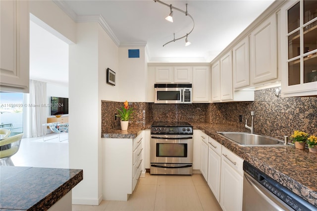 kitchen featuring track lighting, sink, decorative backsplash, light tile patterned floors, and stainless steel appliances